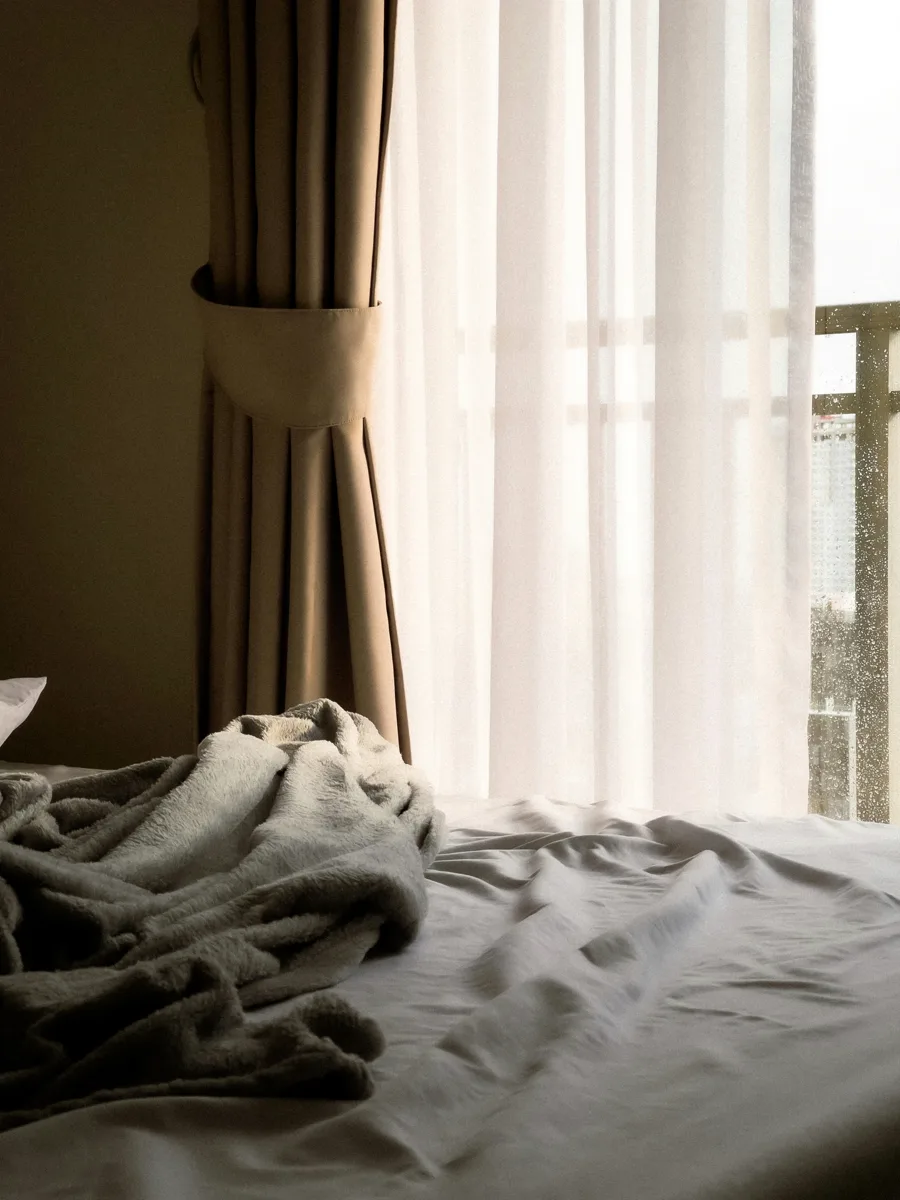 Sheer curtains drawn over a bedroom window in morning light.