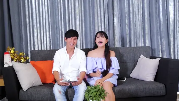Singer Lý Hải and Minh Hà laughing on a sofa.